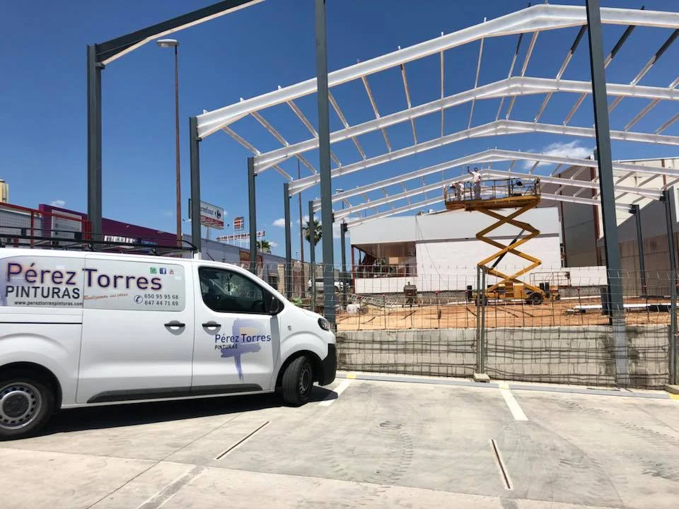 Vehículo de Pérez Torres Pinturas junto a la estructura metálica de una nave en construcción